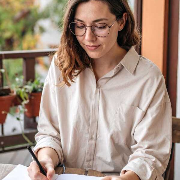 a-mom-in-white-blouse-writing-down-goals-in-how-to-achieve-realistic-goals-as-a-busy-mom