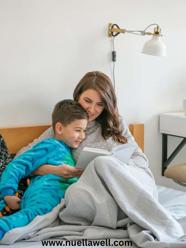 a-mom-tucking-her-child-into-bed-while-reading-a-bedtime-story-in-how-to-reset-your-child's-sleep-schedule-before-school-starts