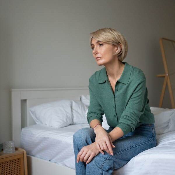 a-woman-sitting-on-the-bed-in-a thoughtful-mood-on-why-moms-ignore-their-own-symptoms